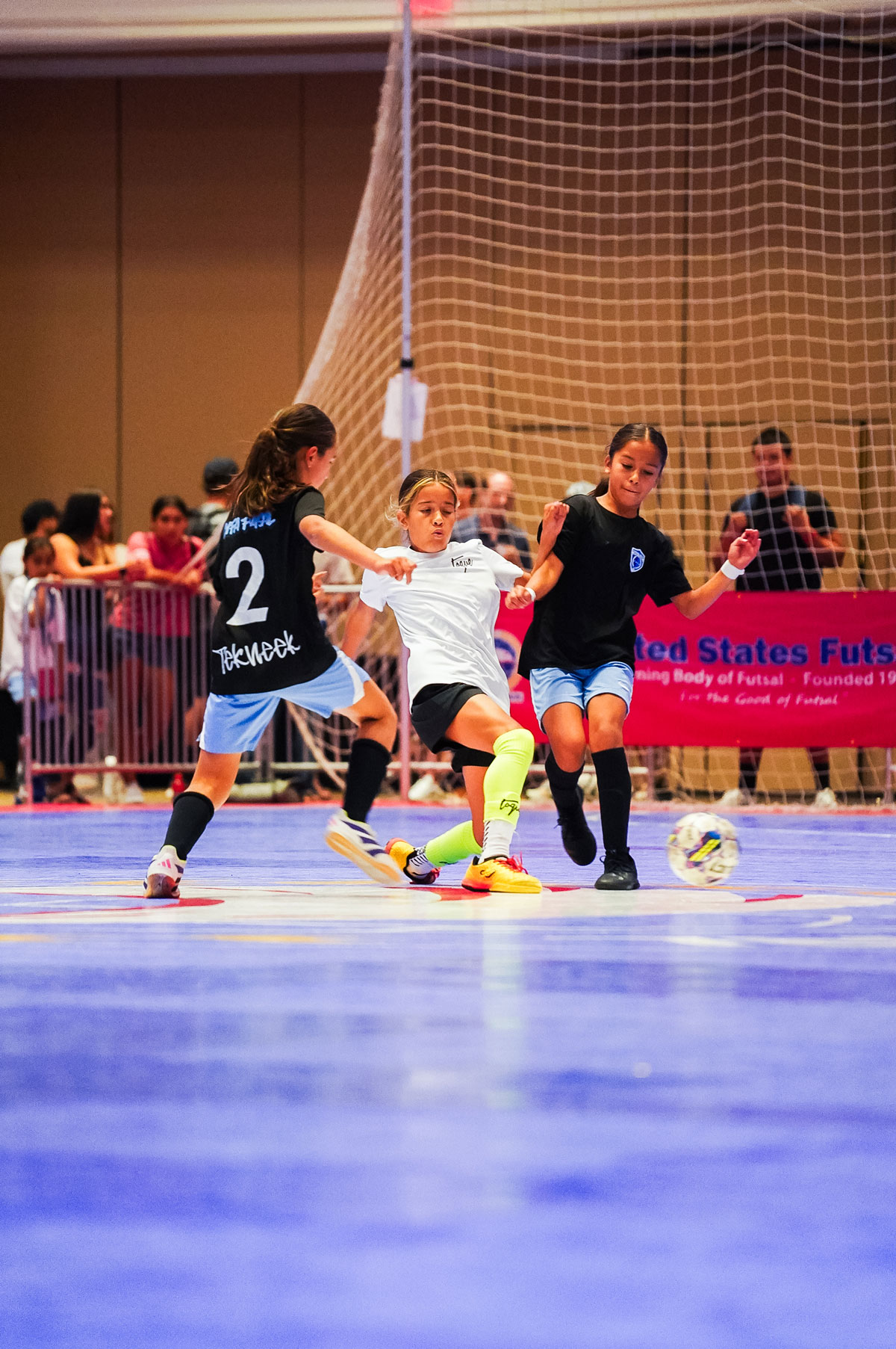 Three young girls working for control of futsal ball